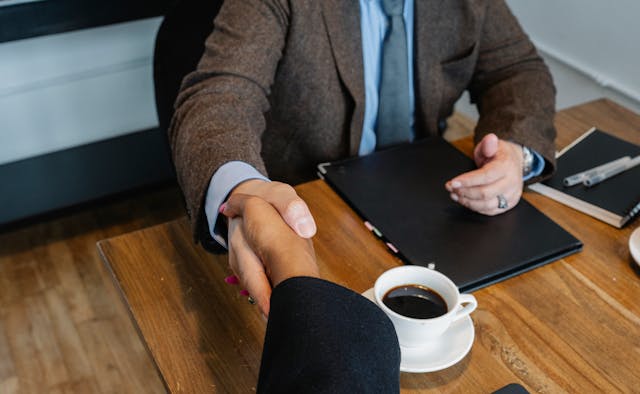 Two people shaking hands over a folder