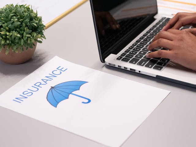 a paper with the word insurance next to someone working on a computer