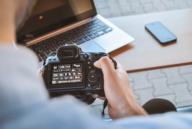 person adjusting the settings of a dslr camera