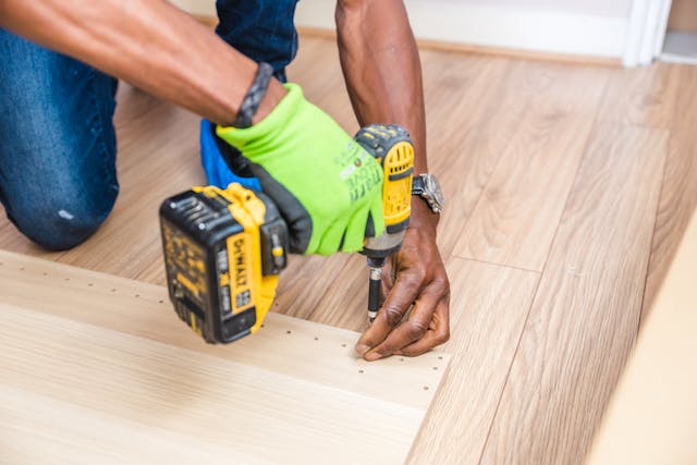 person-using-a-drill-to-screw-something-into-wooden-planks